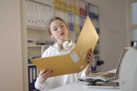 Accountant - Thoughtful female office worker with folder in workplace