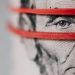 Financial Analys - Closeup of rolled United States five dollar bills tightened with red rubber band